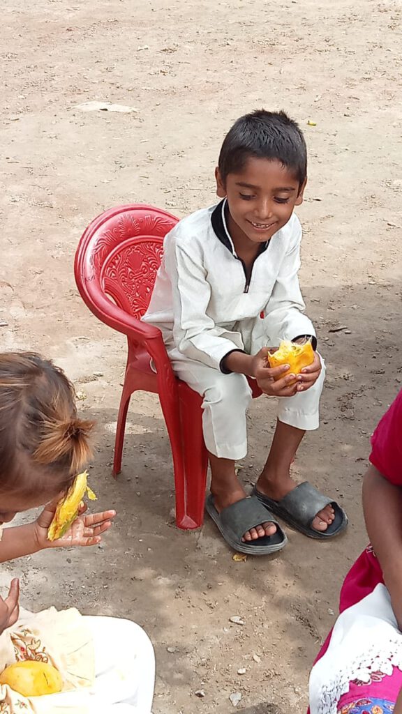 Ein junger Schüler sitzt in einem Stuhl und genießt eine Mango